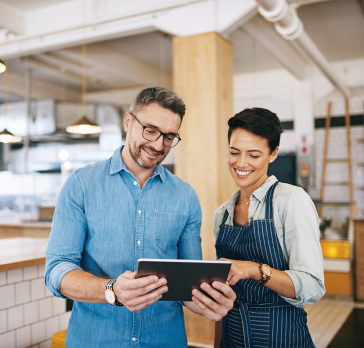 Shot of a man and woman using a digital tablet together in their coffee shop